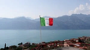 a flag flying on top of a hill next to a body of water