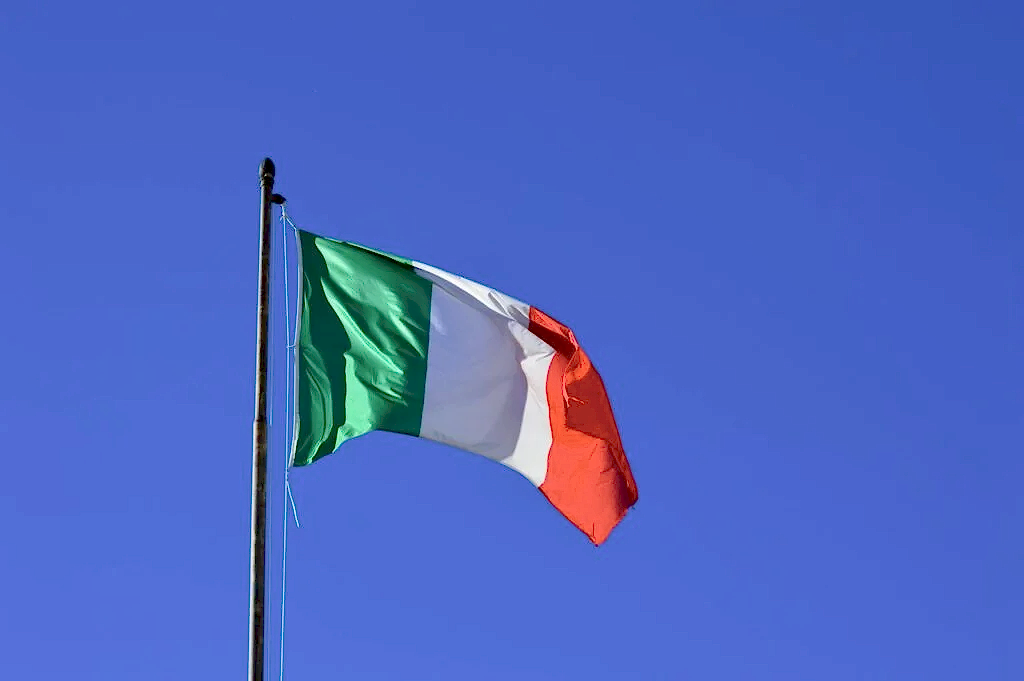 Italian flag flying against a vibrant blue sky, symbolizing national pride and identity.