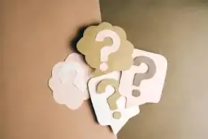 Question mark cutouts in layered paper craft style on a brown backdrop, conceptual art.